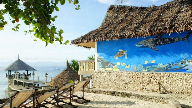 A beachside lounge with thatched-roof structures, a mural of marine life, and a view of the sea. - Asian Belgian Resort (Moalboal)