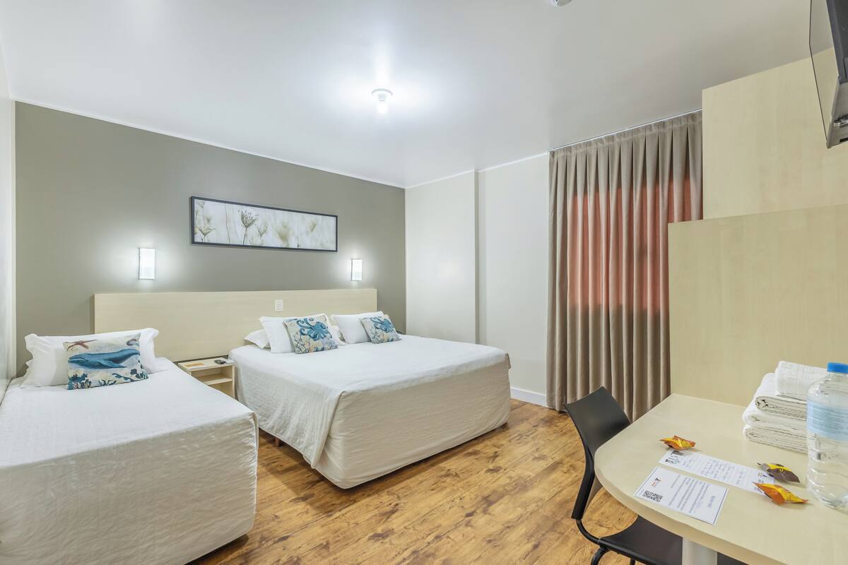 A hotel room with a bed, a desk, and a chair.