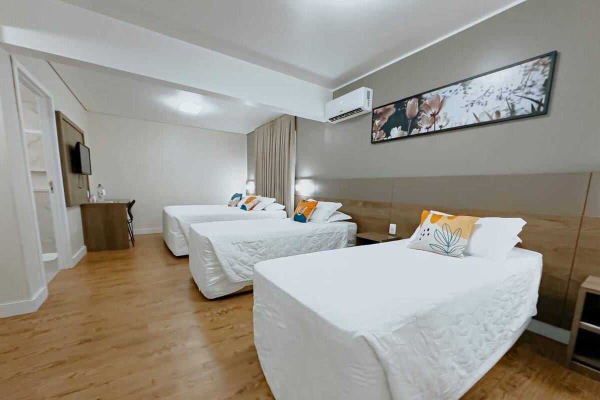A hotel room with two beds, a desk, a chair, and a painting on the wall.