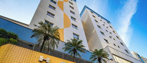 A hotel with a prominent sign, a modern facade, and a clear sky.