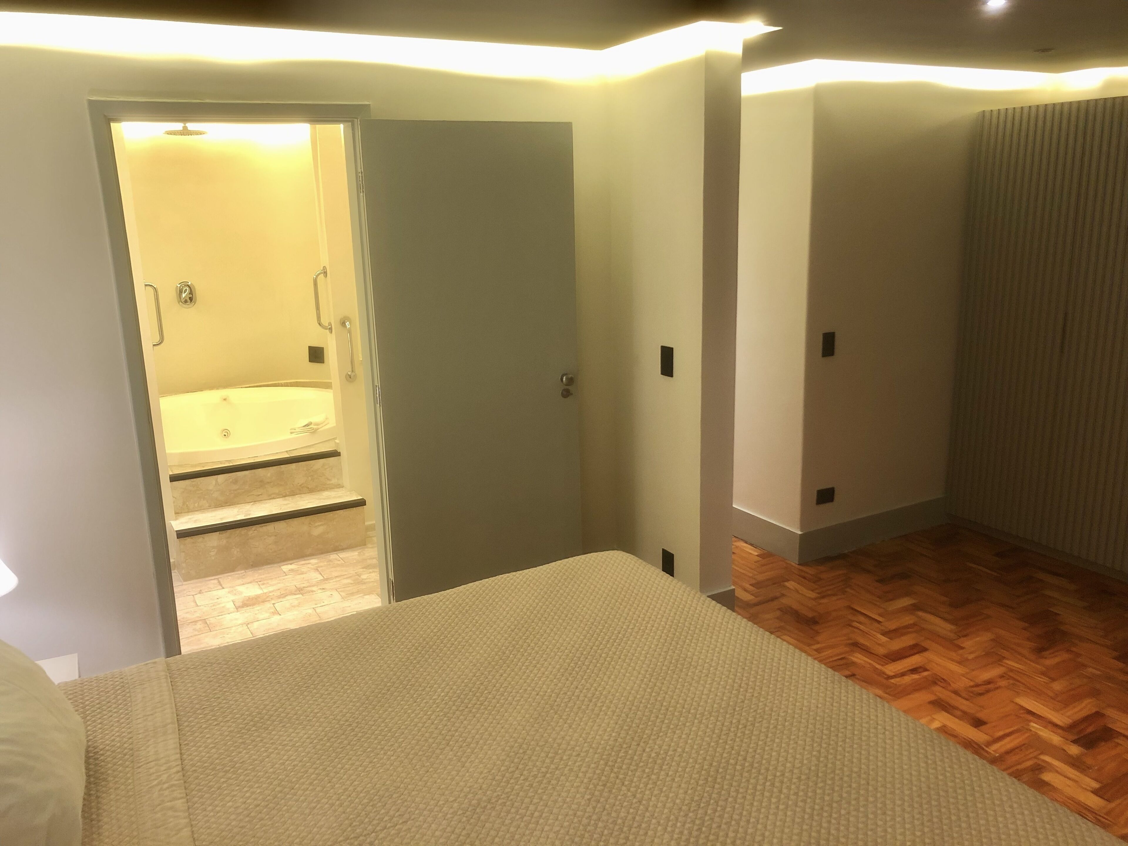 Una habitación con cama, baño con bañera y piso de madera.