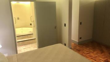 Una habitación con cama, baño con bañera y piso de madera.