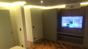 Una habitación moderna con piso de madera en espiga, una cama, un televisor montado en la pared y un equipo de aire acondicionado integrado.