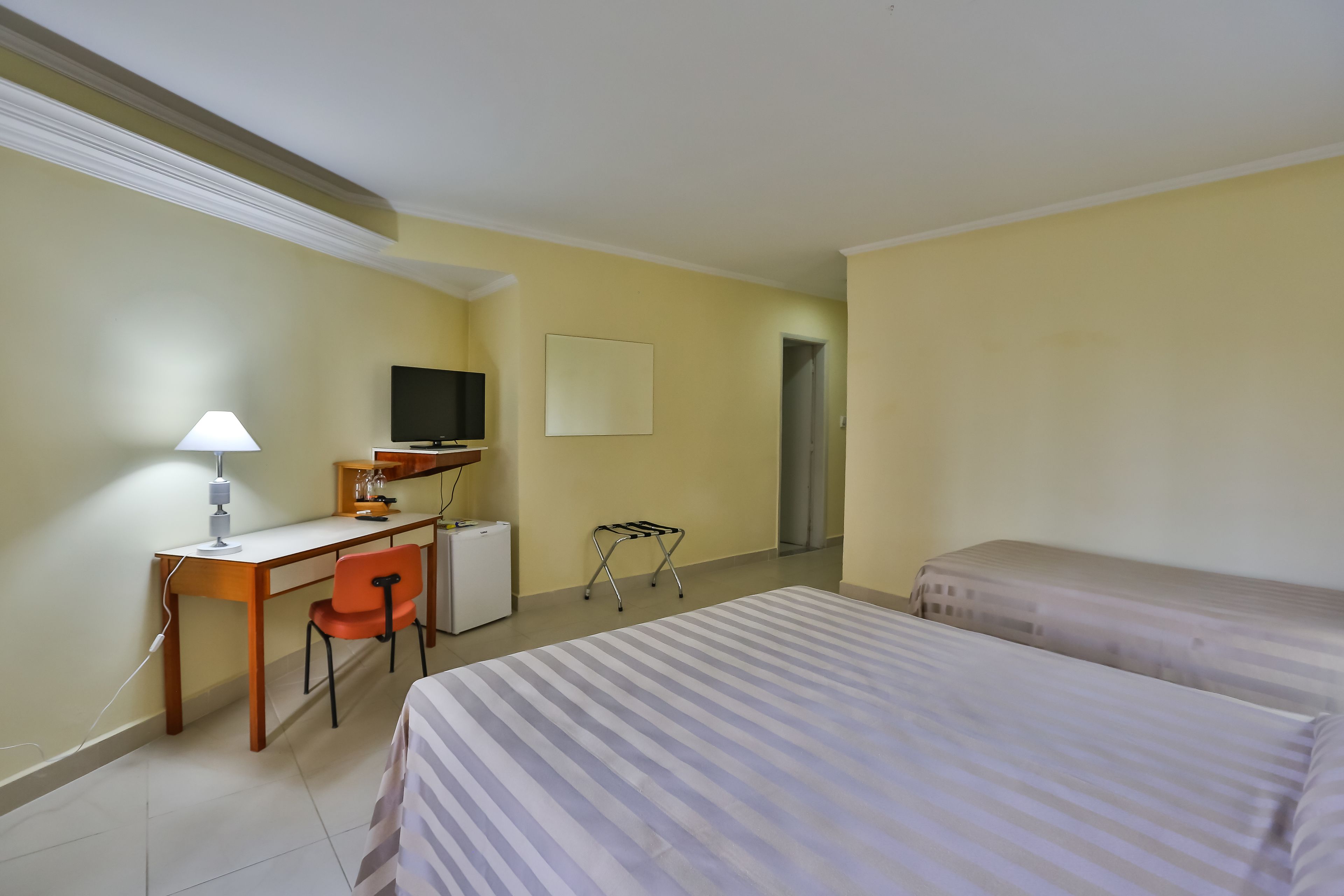 Ein Hotelzimmer mit Bett, Schreibtisch, Stuhl, Fernseher und kleinem Kühlschrank.