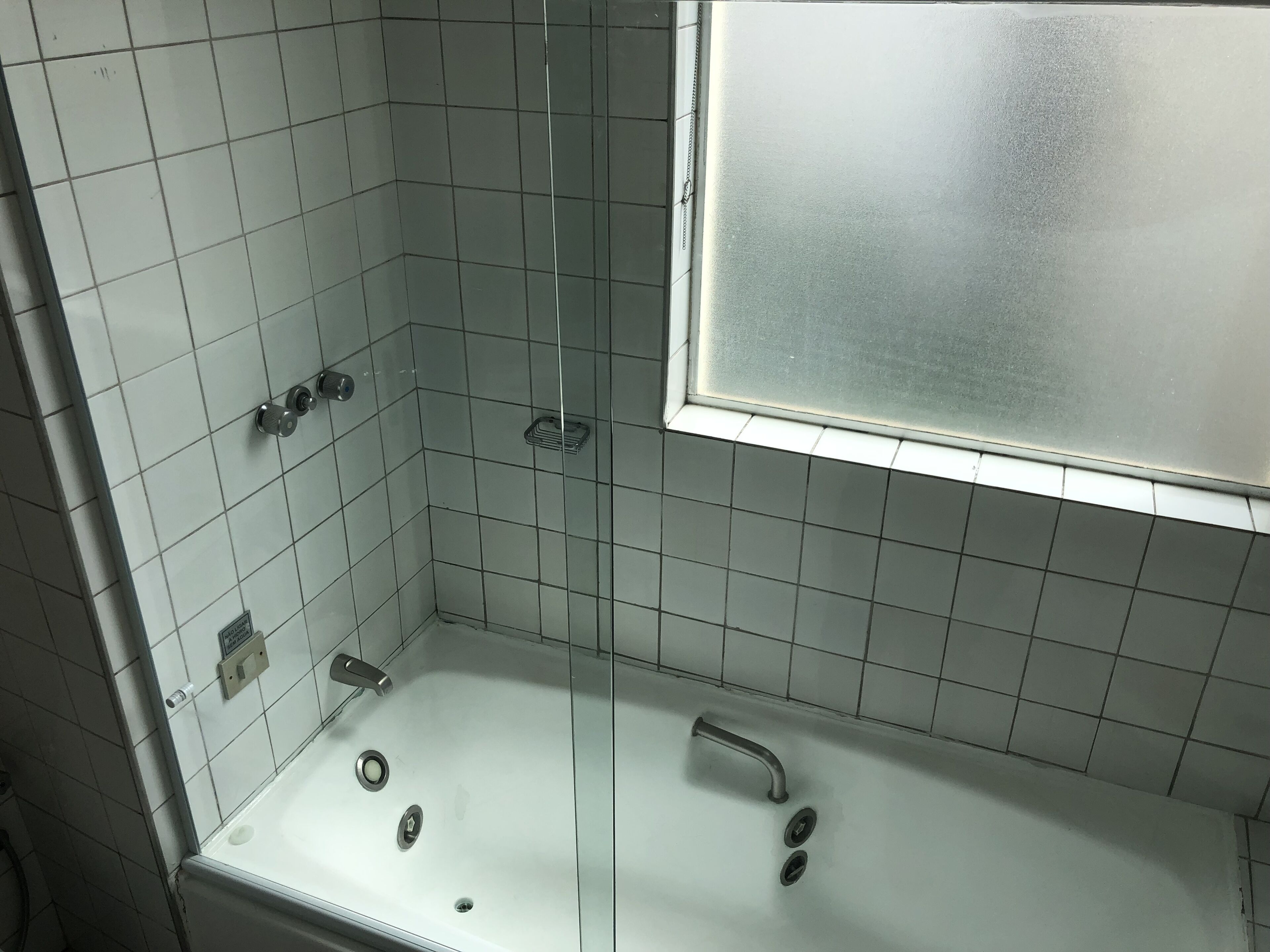 A bathroom with a white bathtub, a shower area, and a frosted glass window.
