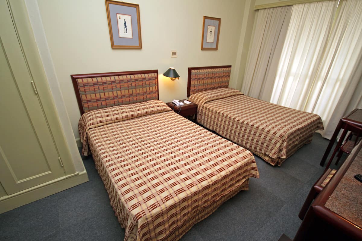 Une chambre d’hôtel avec deux lits, un bureau et une chaise.