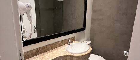 A modern bathroom with a large mirror, a sink, and a toilet.