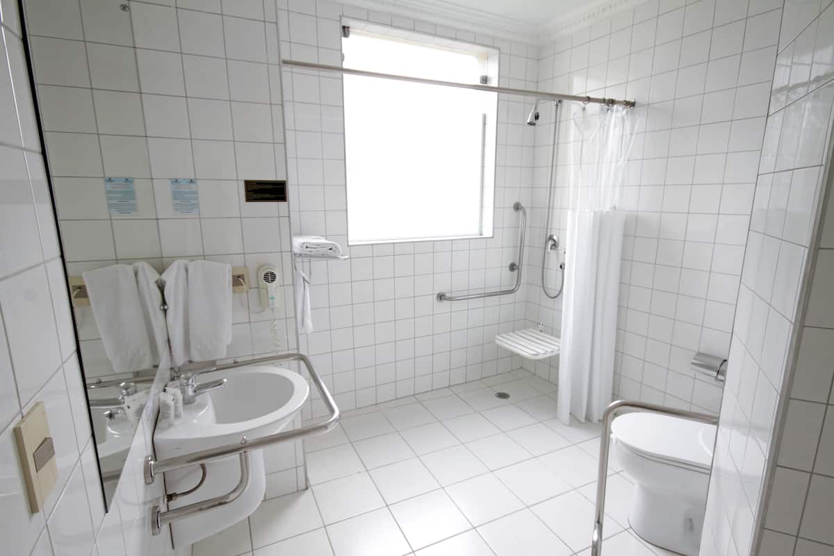 Une salle de bain moderne avec un lavabo blanc, une douche dotée d’une porte en verre et des toilettes.
