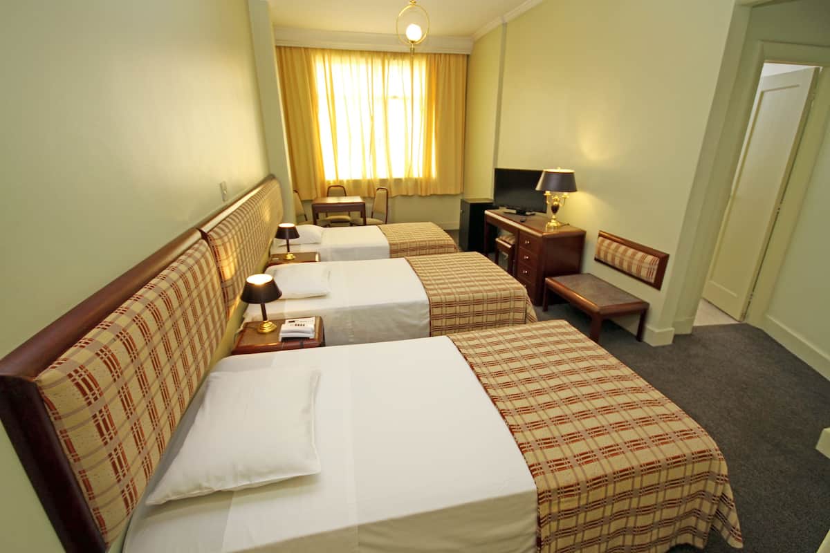 Une chambre d’hôtel avec deux lits, un bureau, une chaise, une télévision et une lampe.