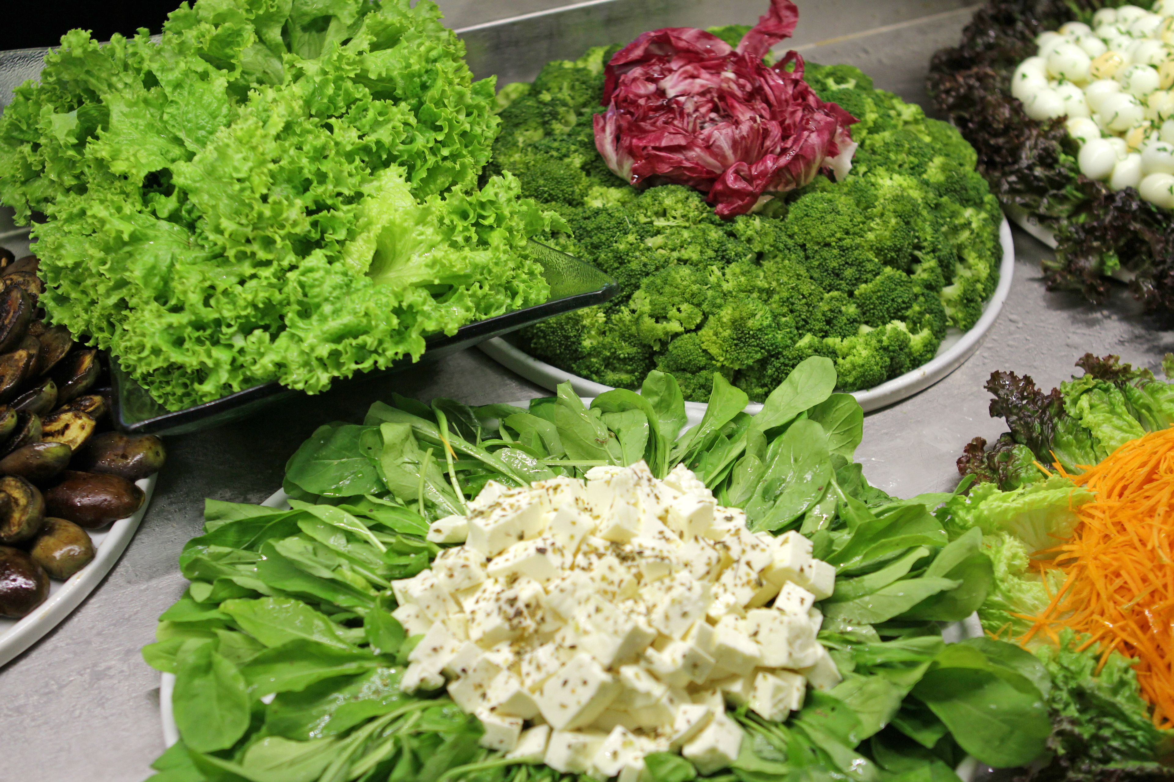 Forskellige friske grøntsager, herunder broccoli, salat og gulerødder, på et bord.