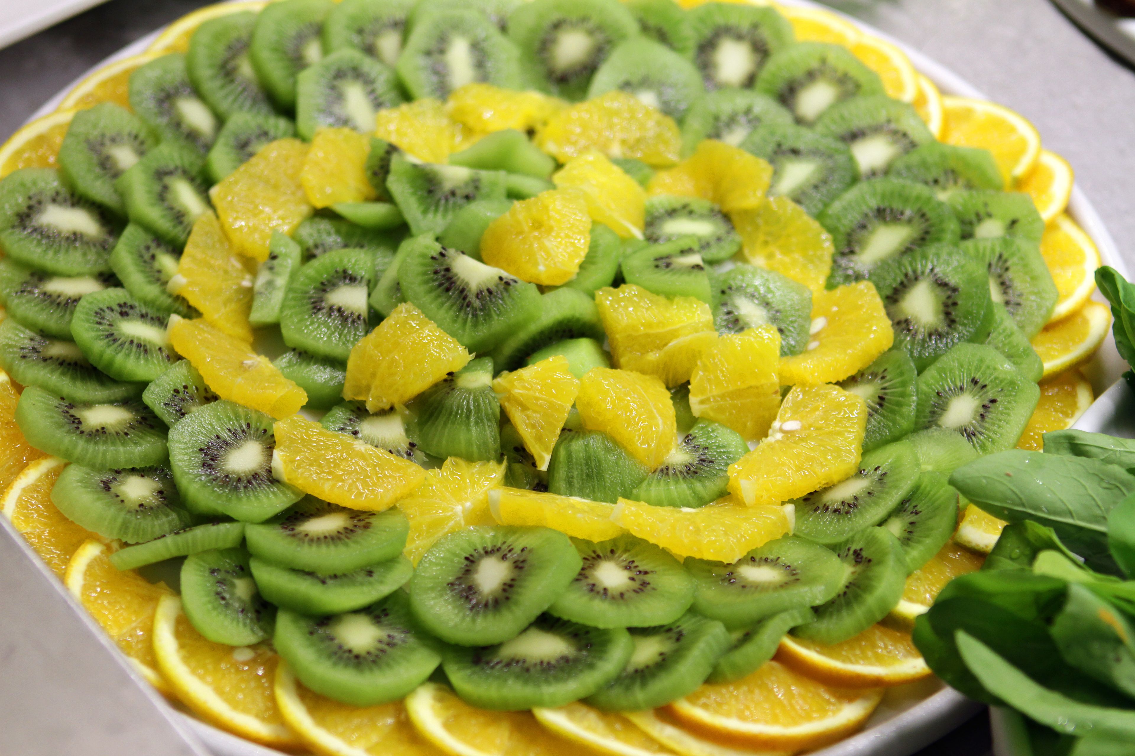 Un piatto di frutta con kiwi, arance e ananas a fette.