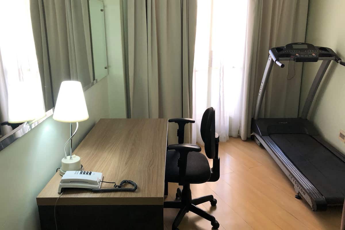 Une chambre d’hôtel équipée d’un bureau, d’une chaise, d’une lampe, d’un téléphone et d’un tapis de course.