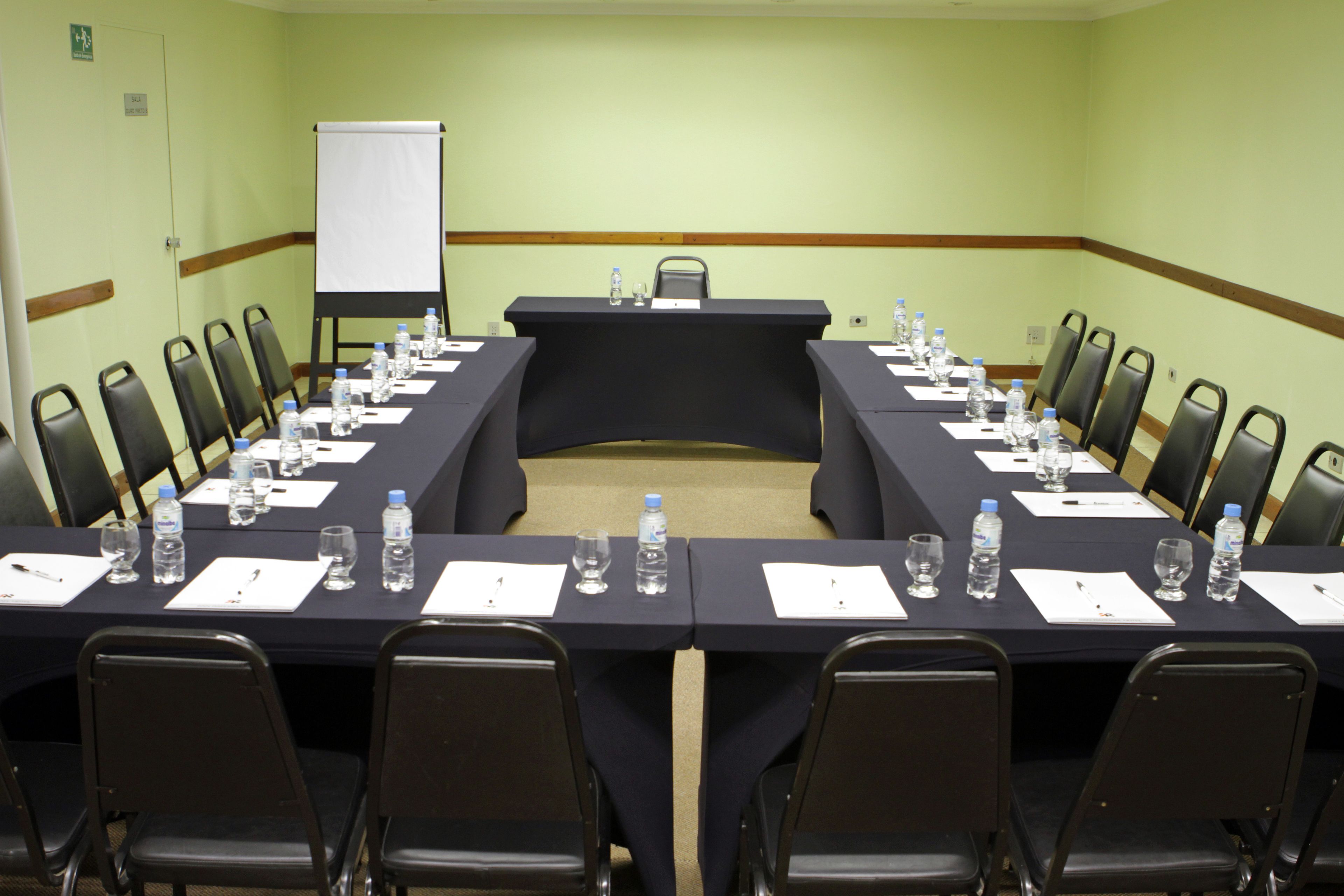 A conference room with a long table, chairs, water bottles, and a whiteboard.