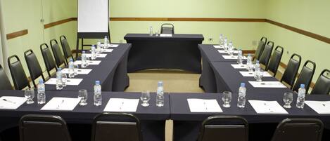 A conference room with a long table, chairs, water bottles, and a whiteboard.