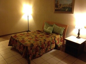 A bedroom with a bed, a nightstand, and two lamps.