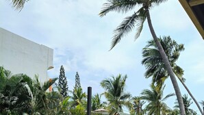 A wooden play structure with slides and a rope barrier, surrounded by palm trees and greenery. - Hotel Surf Olas Altas (Puerto Escondido)
