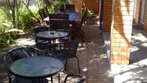 Une terrasse extérieure avec un mur en briques, une table et des chaises.