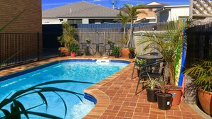 Un jardin avec une piscine, des meubles de patio et des plantes en pot.