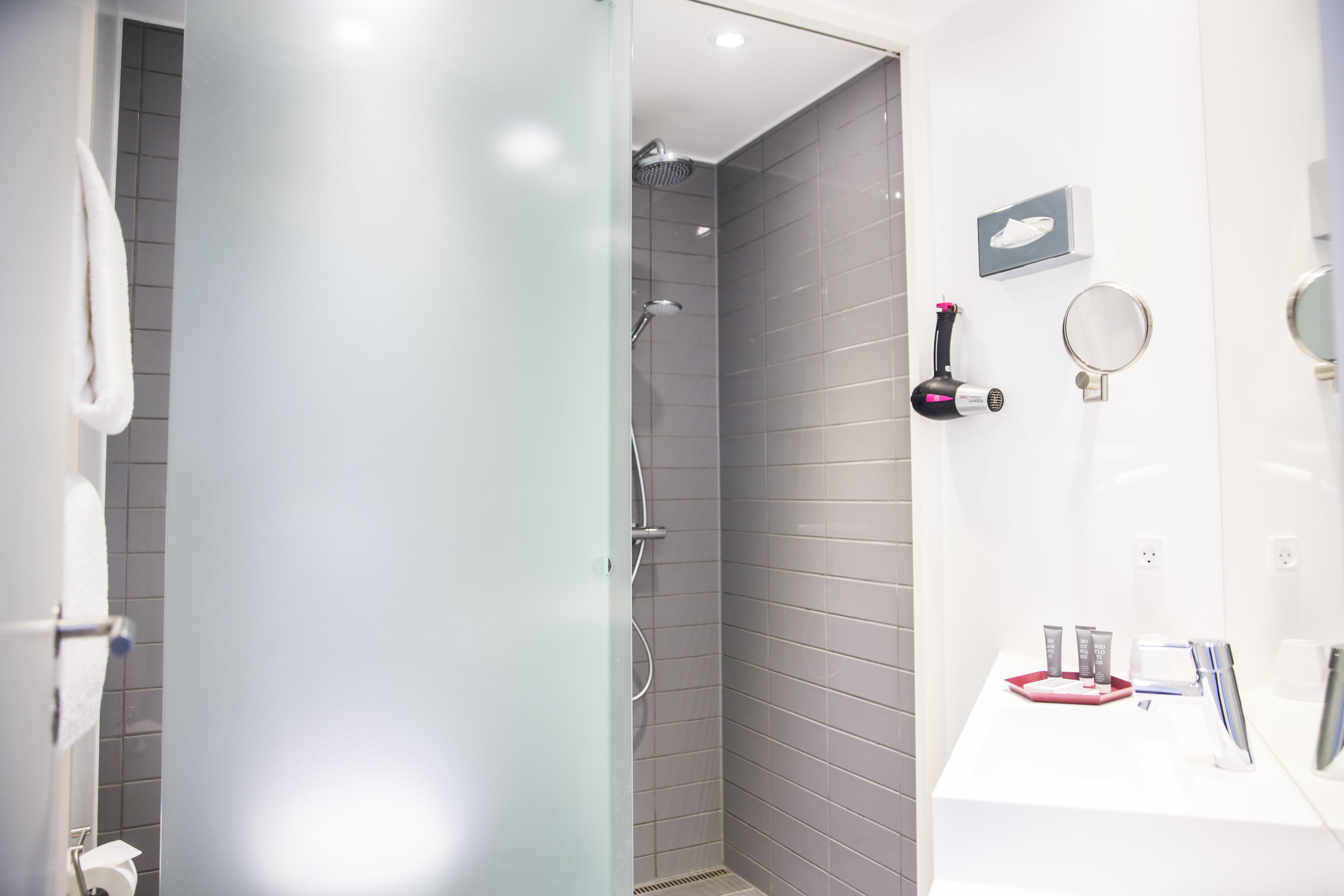 A modern bathroom with a shower, a sink, and a mirror.