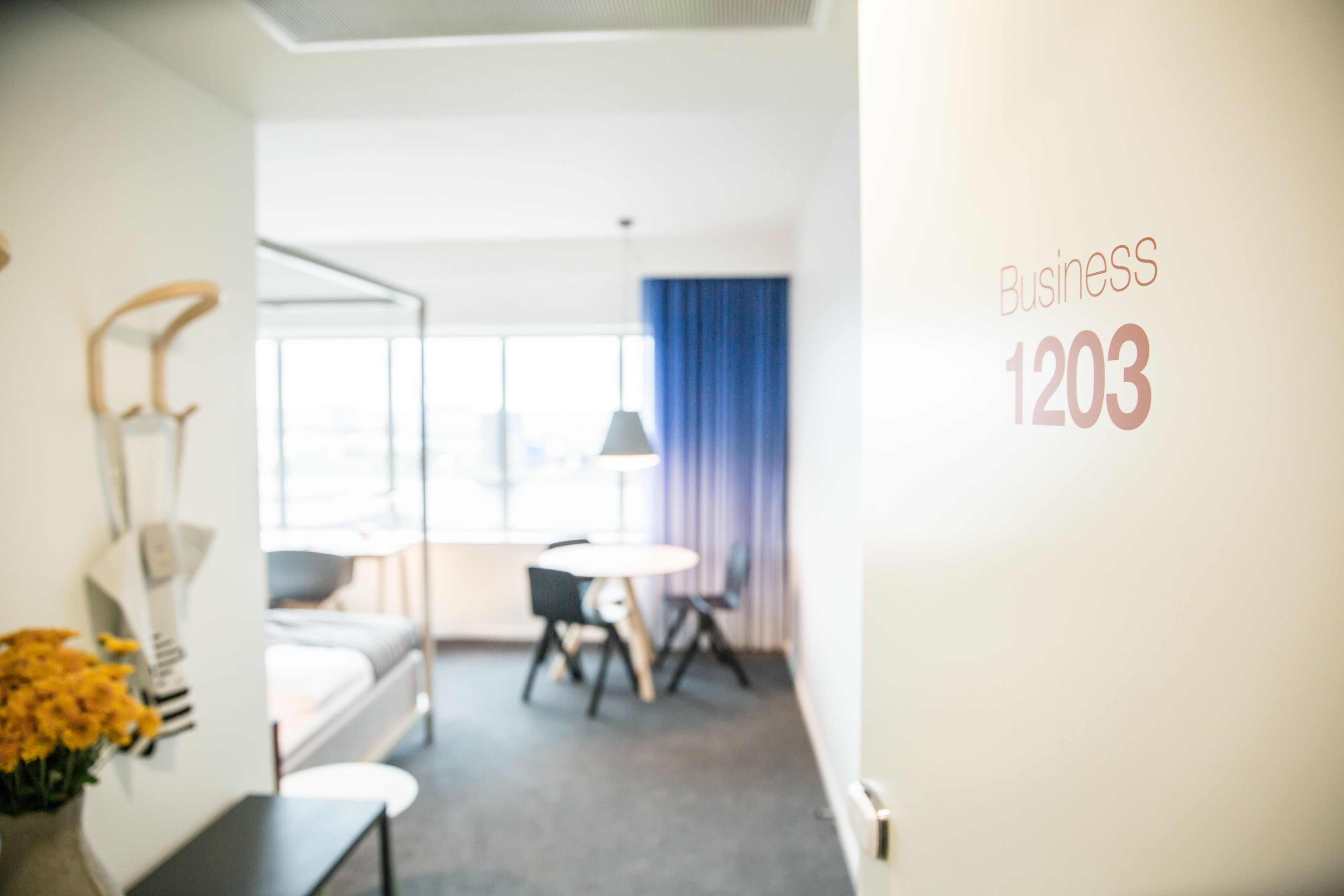 A hotel room with a bed, a desk, a chair, and a window with curtains.