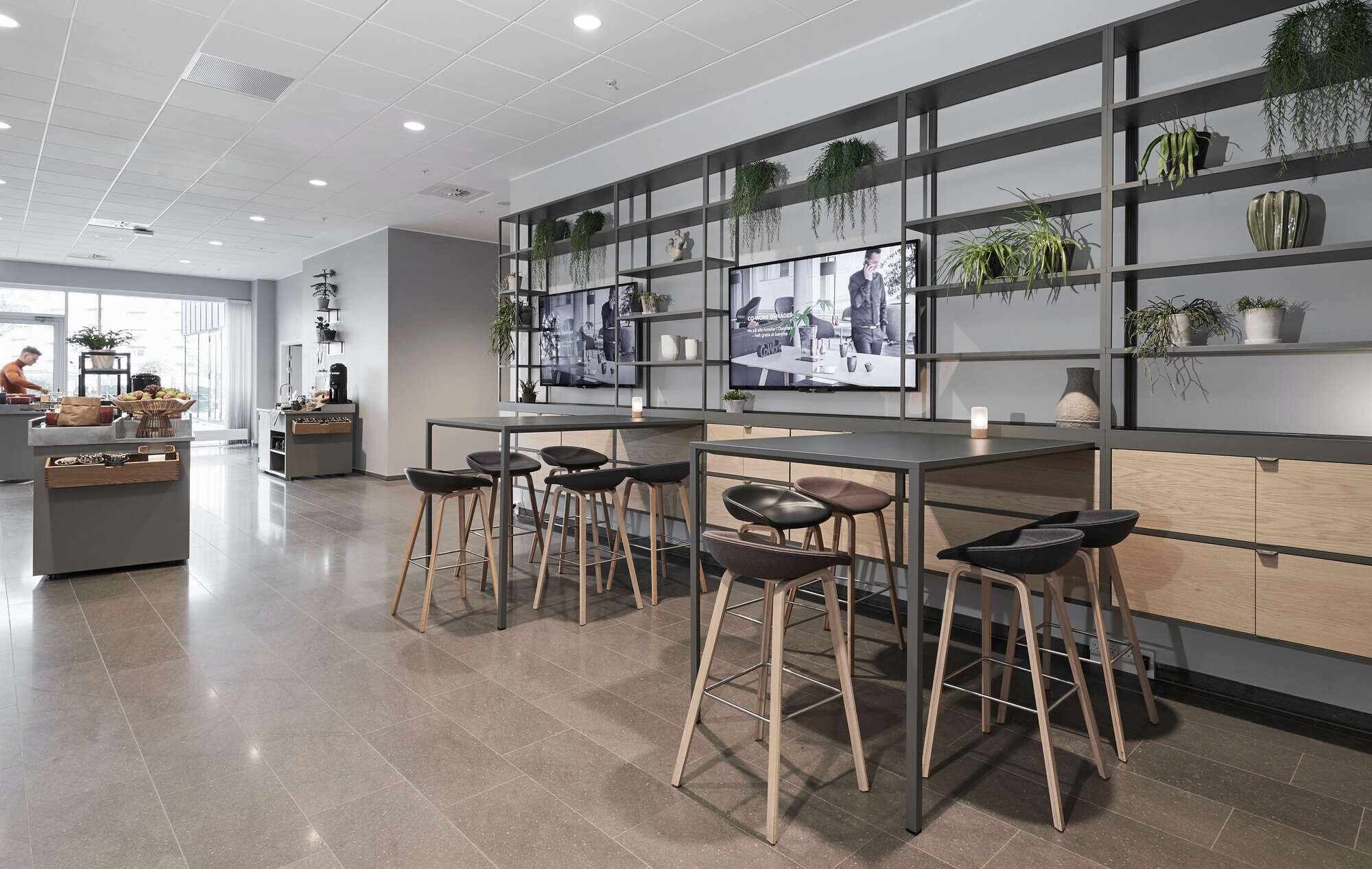 Una cocina moderna con taburetes de bar, un televisor grande y estantes con plantas.
