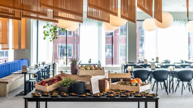 Een buffetopstelling met diverse gerechten en een zithoek met blauwe, beklede banken.