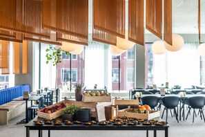 Een buffetopstelling met diverse gerechten en een zithoek met blauwe, beklede banken.
