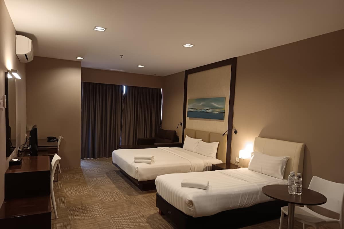 A hotel room with two beds, a desk, a chair, a small table, and a painting on the wall.