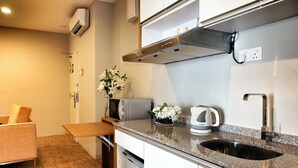 A compact kitchen with a granite countertop, stainless steel sink, and a built-in microwave. - Hotel Primera Suite (Cyberjaya)