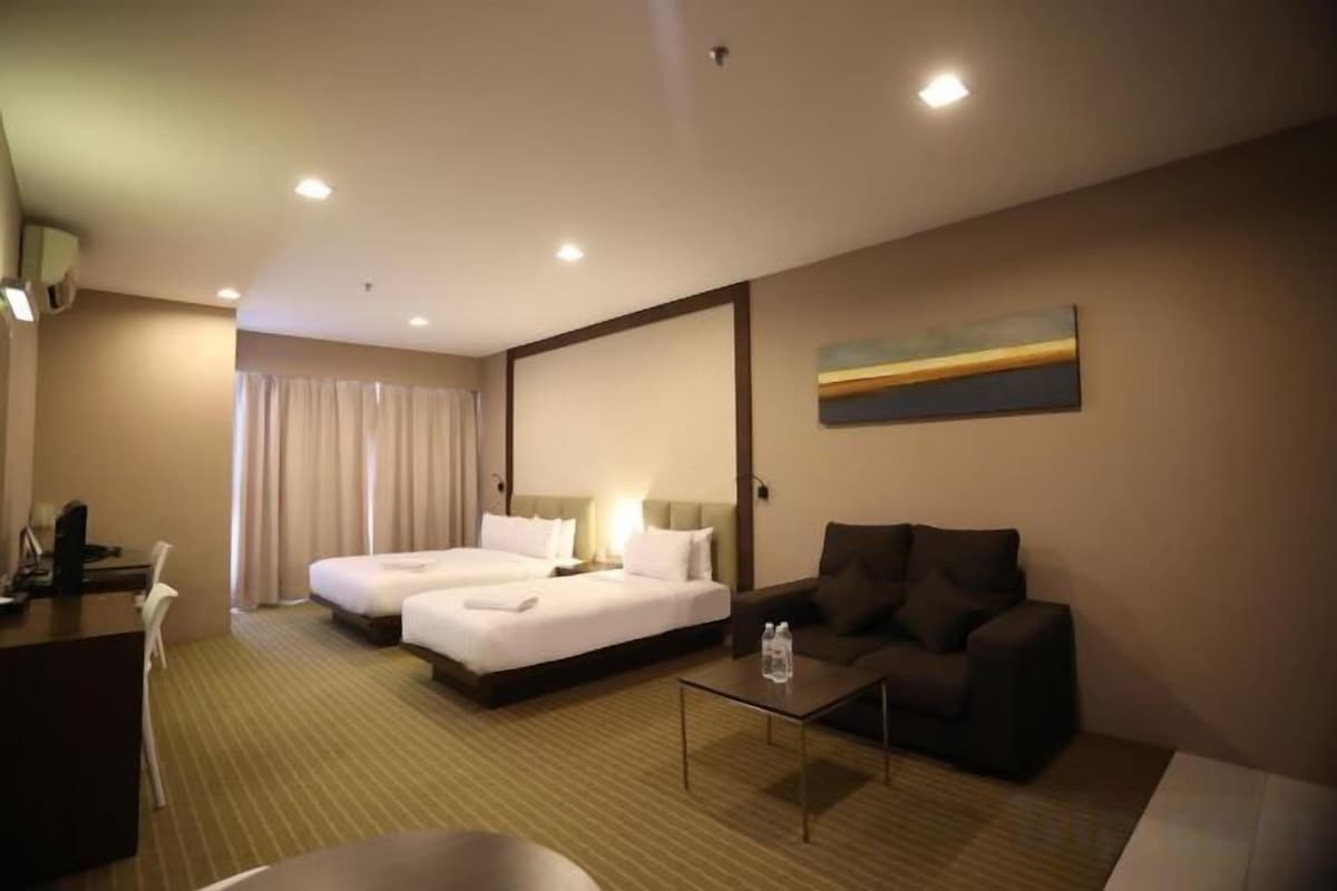 A hotel room with two beds, a desk, a sofa, and a painting on the wall.