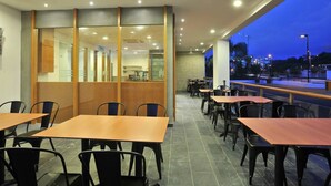 A modern restaurant with indoor seating and a view of the city at dusk. - Hotel Primera Suite (Cyberjaya)