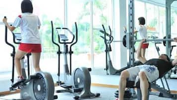 Un gimnasio con equipo de ejercicio, incluyendo cintas de correr y una prensa de banca.