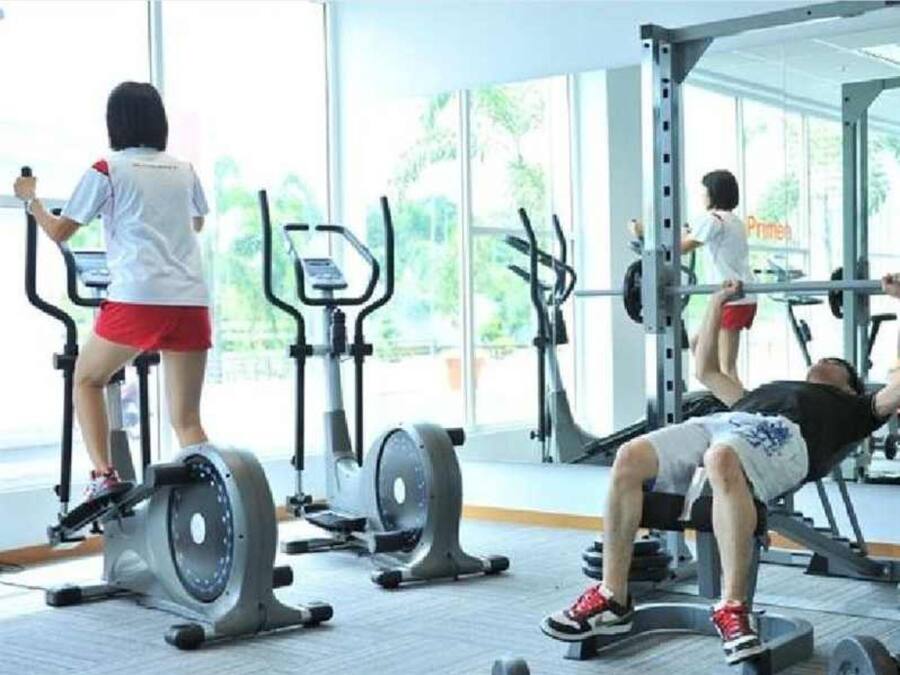 Un gimnasio con equipo de ejercicio, incluyendo cintas de correr y una prensa de banca.