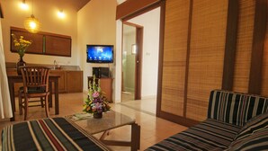 A living room with a sofa, a coffee table, and a TV in the background. - The Studio (Seminyak)