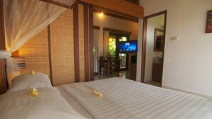 A hotel room with a bed, a television, and a view of the dining area. - The Studio (Seminyak)