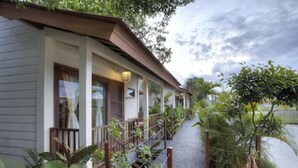 A coastal building with a covered porch, a pathway leading to the water, and lush greenery. - The Studio (Seminyak)