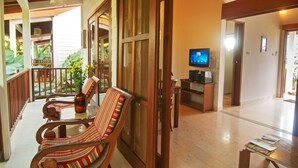 A spacious living area with a wooden floor, a television, and a dining table with chairs. - The Studio (Seminyak)