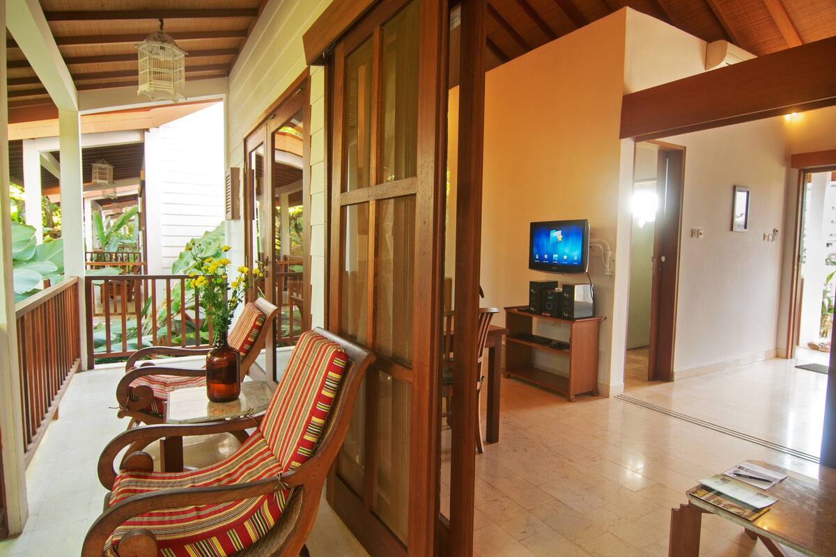 A spacious living area with a wooden floor, a television, and a dining table with chairs.