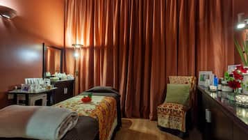 A hotel room with a bed, a chair, a desk with toiletries, and a mirror.