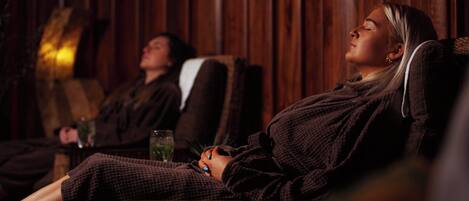 A person relaxing in a chair with a wooden wall in the background.