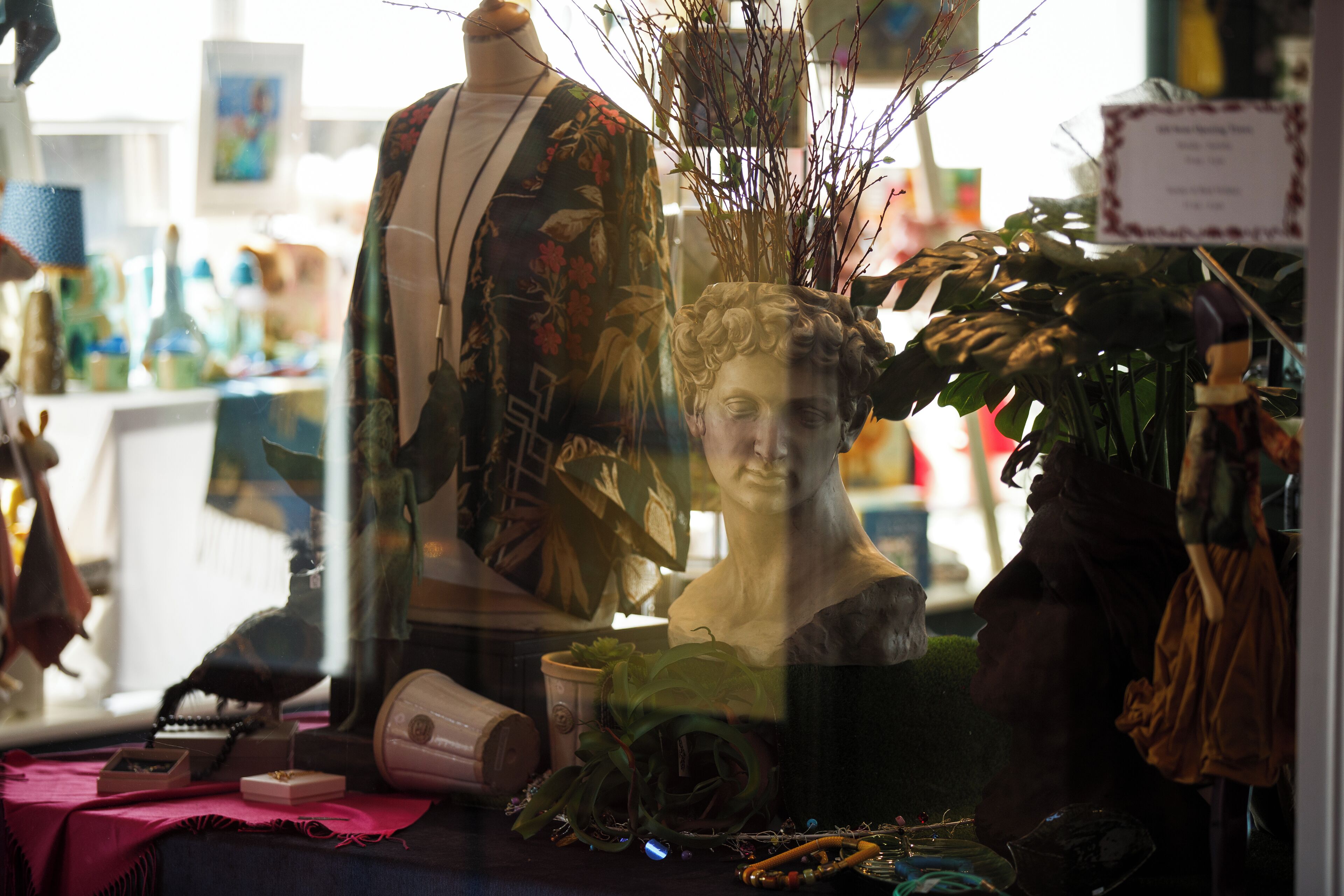 A mannequin dressed in a patterned robe, a bust sculpture, and various decorative items on a table.