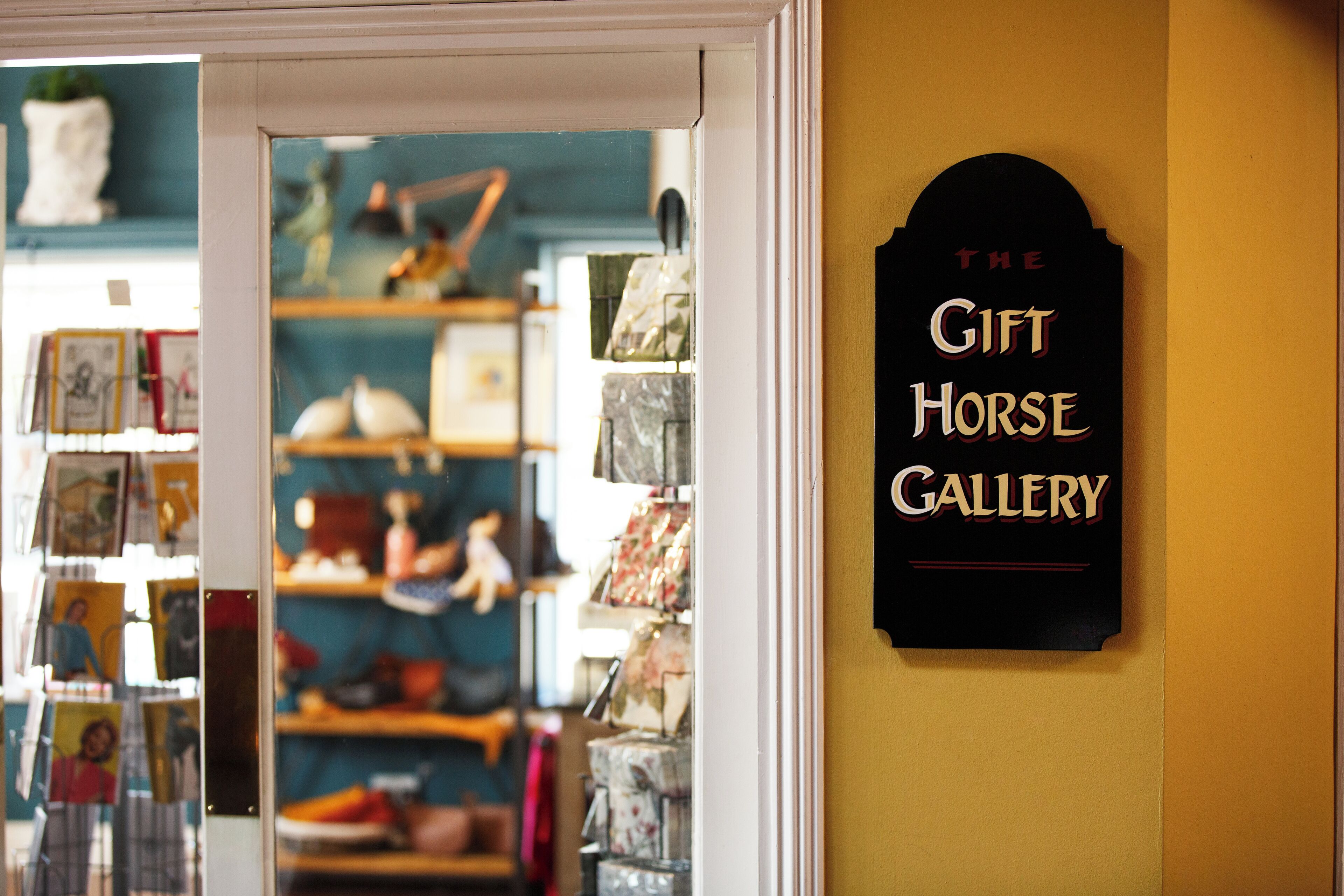 A storefront with a sign reading "The Gift Horse Gallery" and various items displayed inside.