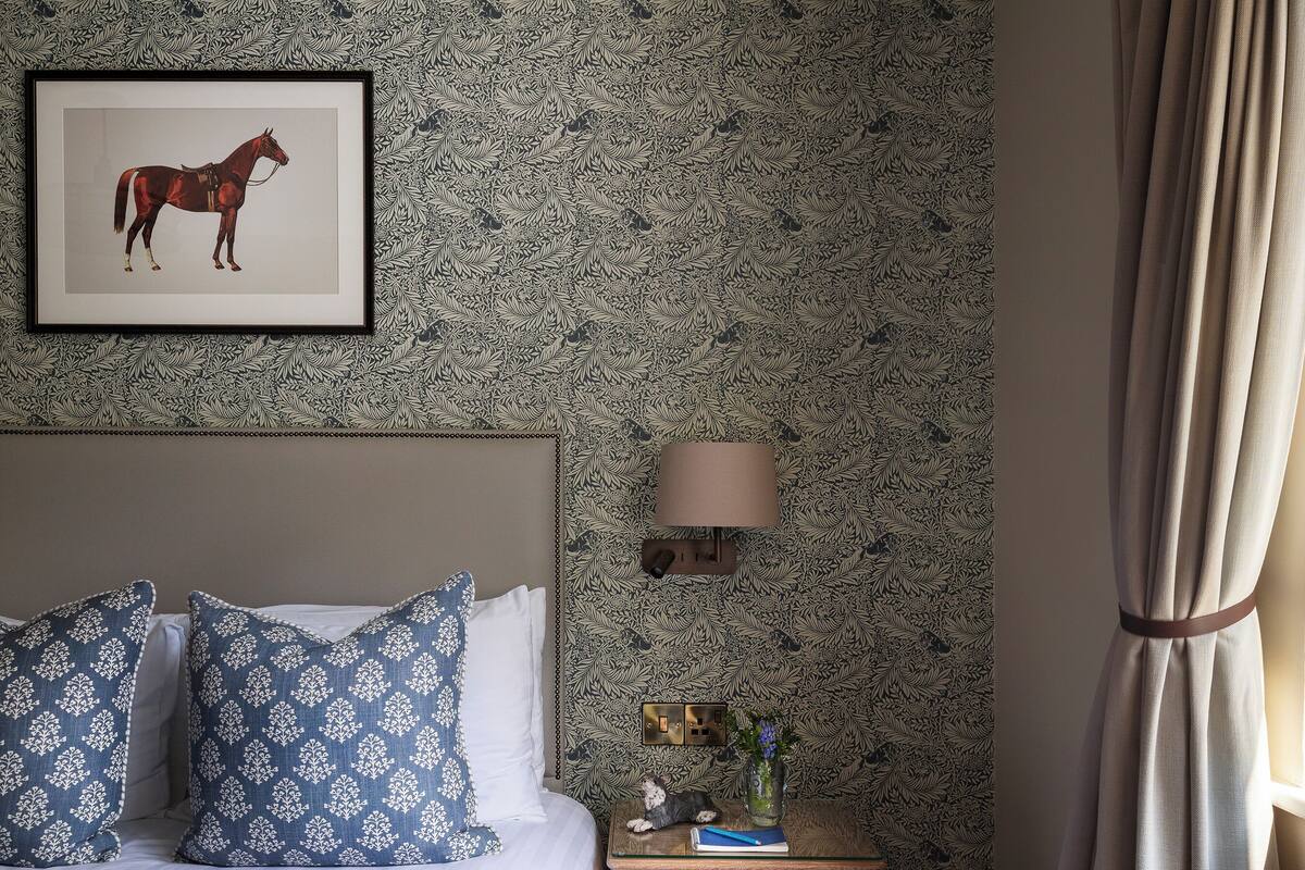 Une chambre à coucher avec un lit, une table de chevet, une lampe et un tableau encadré au mur.