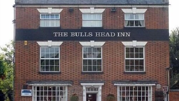 A two-story brick building with a sign reading "The Bulls Head Inn".