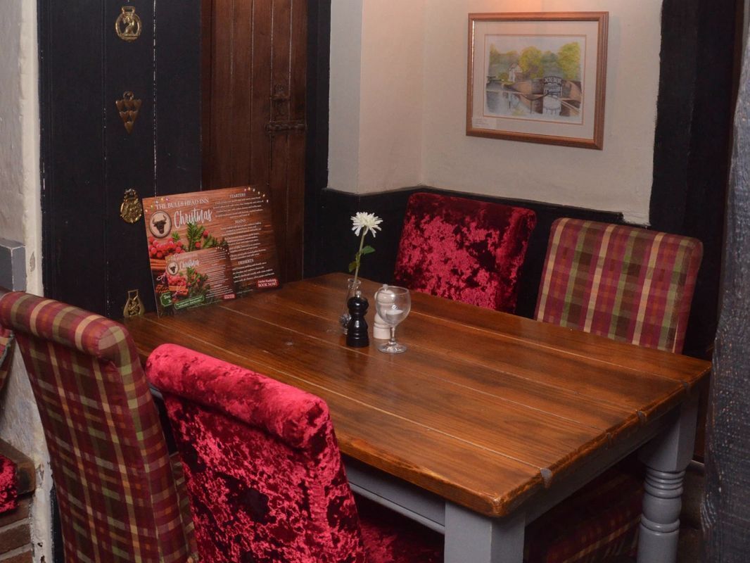 A dining area with a wooden table, red upholstered chairs, and a framed picture on the wall.