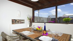 A dining area with a wooden table set for two, white plates, and a bottle of water. - Villas Coral Deluxe (Yaiza)