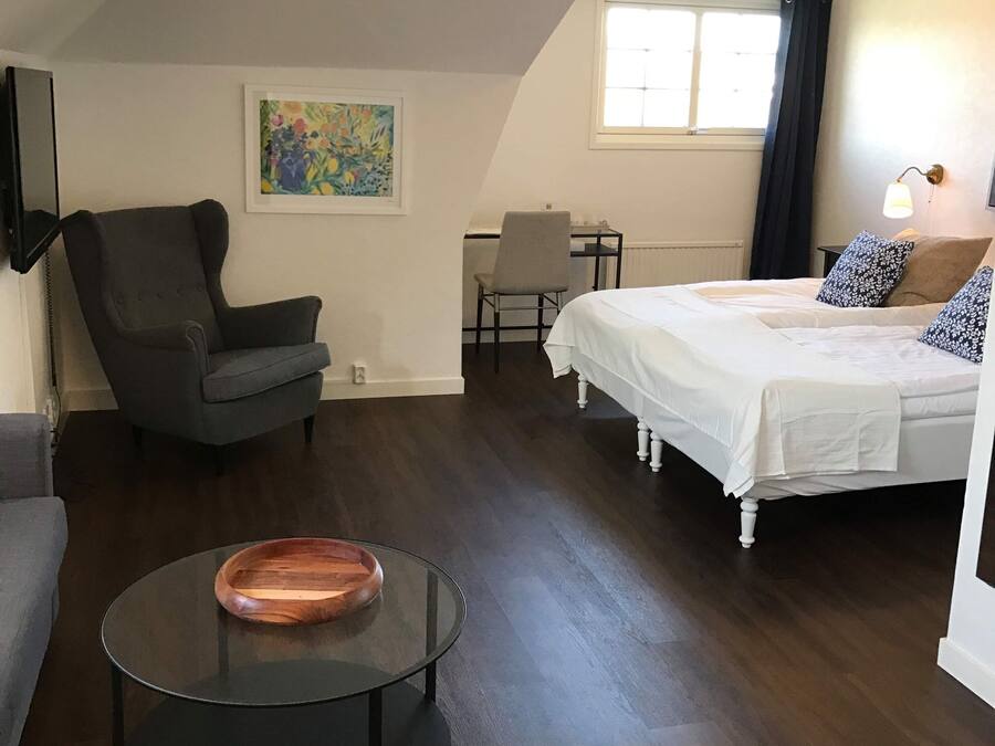 A cozy room with a bed, a chair, a desk, and a coffee table.