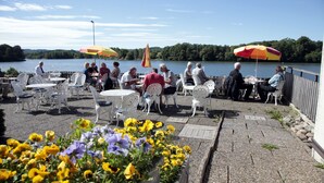 Un patio al aire libre con mesas y sillas, con vista a un lago.