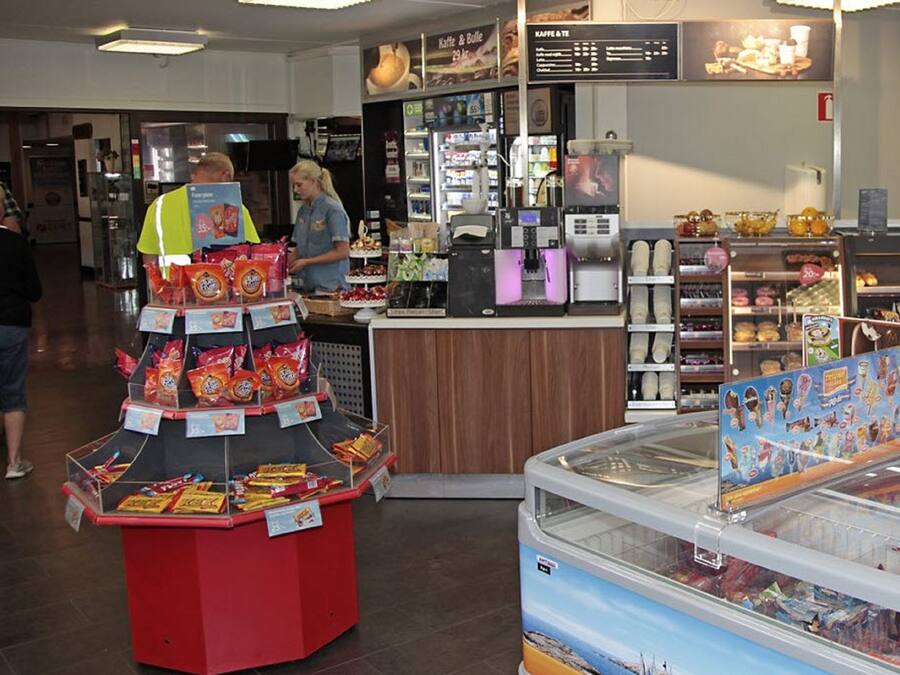 Vitrine de padaria com diversos produtos de panificação e um espaço para café.
