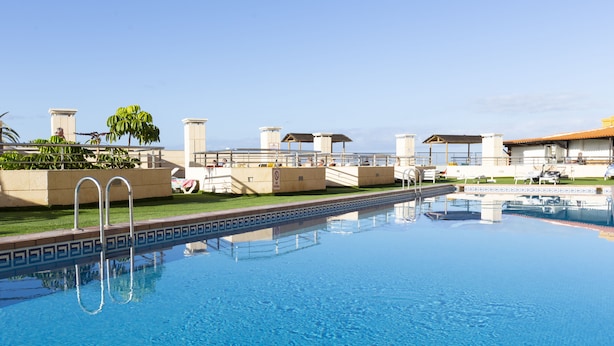 Une piscine à l’eau d’un bleu limpide, entourée d’un petit muret en briques orné d’un motif décoratif.